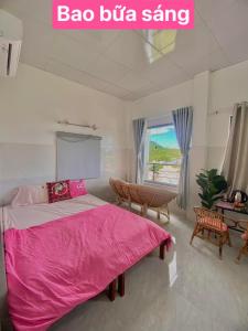 芽庄Homestay Tuyết Trinh的卧室配有粉红色的床、桌子和窗户。