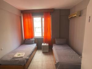 安塔利亚Ersoy Ak Pansiyon的客房设有两张床和一个带橙色窗帘的窗户。