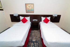 麦加فندق دار الريس - Dar Raies Hotel的两张位于酒店客房的床铺,配有红色枕头