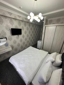 撒马尔罕IMAM AZAM HOTEL的卧室配有白色的床和电视。