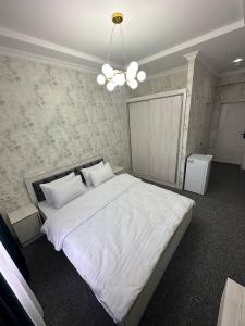 撒马尔罕IMAM AZAM HOTEL的卧室配有一张带吊灯的大型白色床。