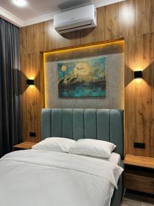 塔尔迪库尔干Sunrise Hotel的卧室配有一张床,墙上挂有绘画作品