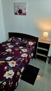 Petit RaffraySK Residence的一张带紫色棉被和鲜花的床