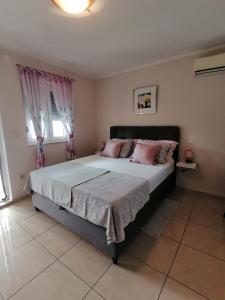 罗佐瓦克Apartmani Marijana的卧室配有一张带粉红色枕头的大床