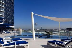 迪拜Everluxe Palm Views 3 Bedroom的一个带椅子的庭院和一个带遮阳伞的游泳池