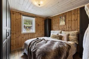 高尔Cozy cabin with sauna, ski tracks and golf outside的卧室配有一张床铺,位于带木墙的房间内