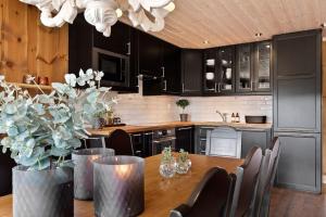 高尔Cozy cabin with sauna, ski tracks and golf outside的一间带木桌的厨房和一间带黑色橱柜的厨房