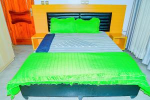 基加利Venus VIP VILLA SUITES的一间卧室配有一张带绿色枕头的床