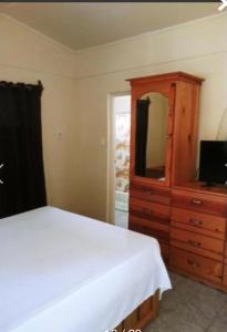 尼格瑞尔Andre's Guest House的一间卧室配有一张床和一个带镜子的梳妆台