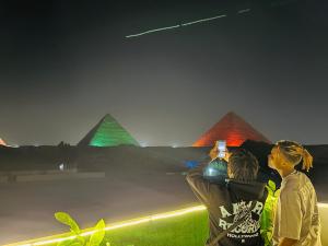 开罗Capital Of Pyramids Hotel的两个人晚上拍金字塔的照片