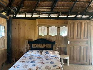 卡塔赫纳Punta Arena EcoHostal and EcoFit – Your Eco-Friendly Oasis 02的卧室配有一张床铺,位于带木墙的房间内