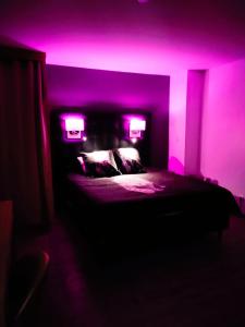 阿格德角Village Naturiste Cap d'Agde L' Eden 208的紫色的房间,床上有两个灯