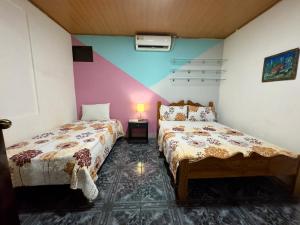 奎波斯城Casa Quepos的一间卧室设有两张床和一张桌子上的台灯。