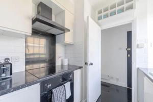 伦敦Cosy Studio in Bethnal Green的厨房配有白色橱柜和炉灶烤箱。
