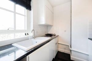 伦敦Cosy Studio in Bethnal Green的白色的厨房设有水槽和窗户