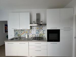 瓦斯托Perla marina的厨房配有白色橱柜和炉灶烤箱。