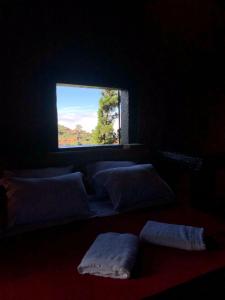 拉夫拉斯诺瓦斯Chalés Serra do Trovão的黑暗的客房配有带白色枕头的窗户。