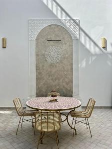 马拉喀什Riad Fisaline en exclusivité pour vous à Marrakech的一个带墙壁的庭院内的桌椅