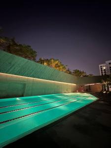 沙迦Al jada apartment Sharjah的夜晚带绿灯的游泳池
