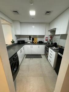 沙迦Al jada apartment Sharjah的一间大厨房,配有白色的橱柜和一台洗衣机