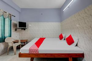 蒂鲁帕蒂OYO Flagship Sai Ganesh Deluxe Lodge的一间卧室配有一张带红色枕头的床和一台电视。