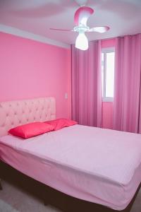 瓜拉派瑞Apartamento rosa的粉红色的卧室配有床和吊扇