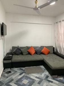 特马Lovely 1-bedroom Unit的客厅配有带橙色枕头的绿色沙发