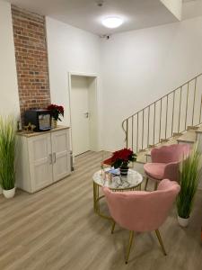 埃姆登Appartementhaus EMDEN的客房设有楼梯、粉红色的椅子和一张桌子