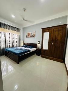 贾夫纳Matheera holiday home的一间卧室配有一张床和一个木制橱柜