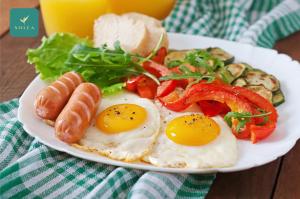 富国SOLÉA Hotel GrandWorld Phu Quoc的包括鸡蛋香肠和蔬菜的早餐食品