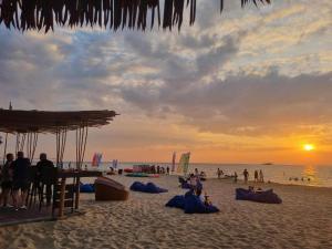 富国SOLÉA Hotel GrandWorld Phu Quoc的日落时分在海滩上一群人
