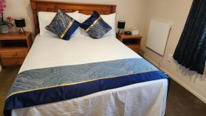 奥克兰Bed & Breakfast @ Unsworth Heights Albany的一间卧室配有一张带蓝色和金色枕头的大床