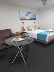 麦夸里港阿斯顿希尔汽车旅馆的一间卧室配有一张床、一张桌子和一张沙发