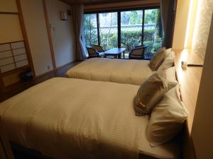 下吕市卡瓦卡米亚旅馆的配有窗户的酒店客房内的两张床