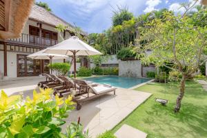金巴兰Villa Dorado - Steps from Jimbaran Beach的后院的形象,带有游泳池和遮阳伞