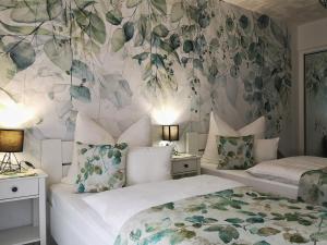 Herend安娜旅馆的卧室内的两张床,配有花卉壁纸