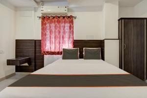 班加罗尔Redkey Transit Hotel Near Bangalore Airport的一间卧室配有一张带红色窗帘的大床
