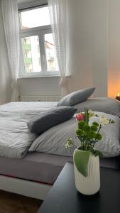 莱比锡Charmante Wohnung in der Südvorstadt的一间卧室配有一张床,一个花瓶摆放在桌子上