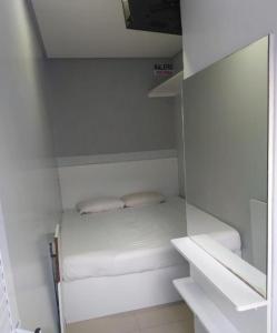 福塔莱萨Pousada Do Futuro的一间白色的小房间,配有床和镜子