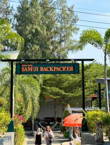 班拉克海滩苏梅岛背包客旅馆的两个女人在读了萨姆特背包的标语下行走