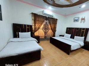 拉合尔Hotel Eden Plus Lahore的一间卧室设有两张床和窗户。