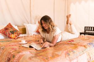 斋沙默尔Desert Dream Royal Camp with Pool的躺在床上读书的女人