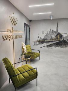 弗罗茨瓦夫Morfeusz Apartamenty Księcia Witolda的一间设有两张绿色椅子和壁画的房间