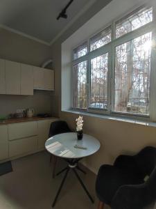 塔什干Alleya Gagarina的厨房配有桌子和两把椅子,设有两扇窗户。