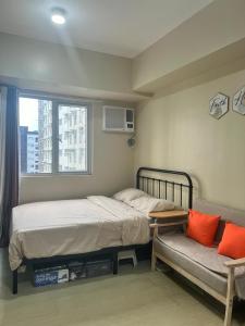 伊洛伊洛New Cute&Cozy Fully Furnished Studio - Avida Towers的一间卧室配有一张床、一张沙发和一个窗口