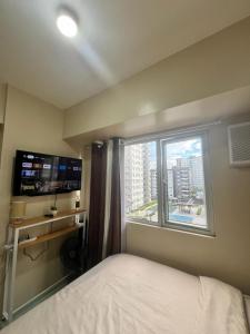 伊洛伊洛New Cute&Cozy Fully Furnished Studio - Avida Towers的一间卧室设有一张床和一个大窗户