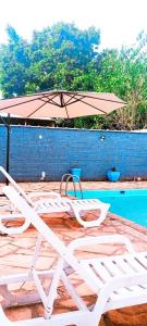 德尔菲诺波利斯HOTEL JP的游泳池旁的一把躺椅和一把遮阳伞