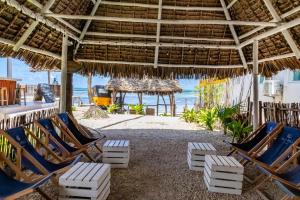 江比阿Pili Pili Oasis的海滩上设有椅子和草伞,海洋