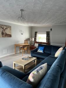 斯特兰拉尔Lochans Lodge的客厅配有蓝色的沙发和桌子