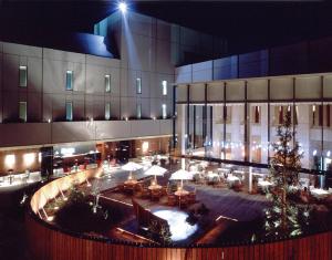 川崎莫利诺新百合丘酒店的一座带庭院的大型建筑,庭院内配有桌椅